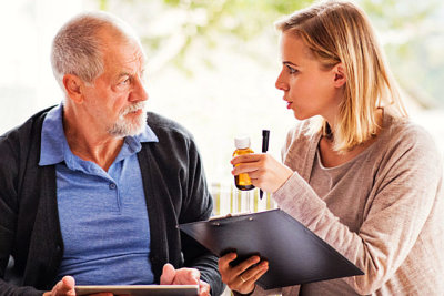 woman holding medicine while talking to old man