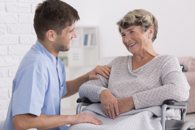 Professional caregiver comforting smiling elderly